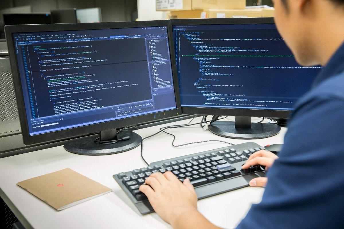 Développeur écrivant du code sur deux écrans