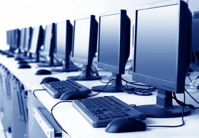Rangée de postes de travail informatiques équipés d'écrans, de claviers et de souris